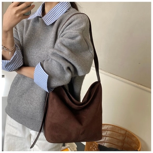 Detail of the soft dark brown suede hobo bag with minimalist shoulder strap on a model