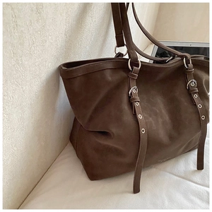 Detail of a large brown tote bag with silver eyelet metal rings and a matte finish texture