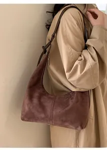 Brown suede dumpling bag with a knotted shoulder strap worn by a model in a trench coat