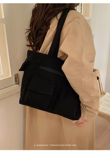 Close-up of black corduroy tote bag featuring flap pockets and thick ribbed texture