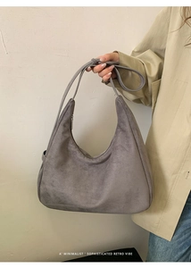 Detail of grey suede hobo bag showing minimalist half-moon structure and soft texture