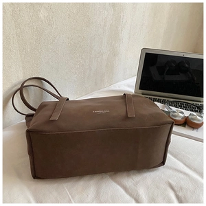 Detail of dark brown leather tote bag with FASHION & BAGS text next to a laptop