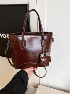 Glossy dark brown retro tote bag with long shoulder strap and small coin purse charm