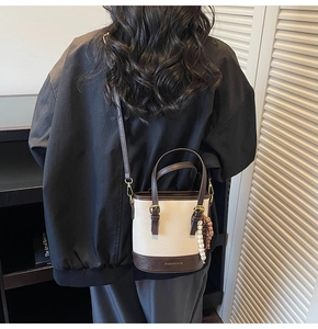 Detail of mini bucket bag in cream and brown PU leather with a beaded tassel charm