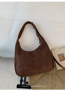Close-up of a dark brown suede tote bag featuring adjustable strap and minimalist texture
