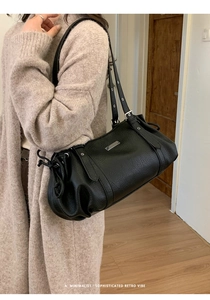 Detail of black pebbled leather shoulder bag with silver metal accent and side drawstring