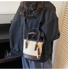 Close-up of a color-blocked bucket bag with wooden bead charm and FASHION logo