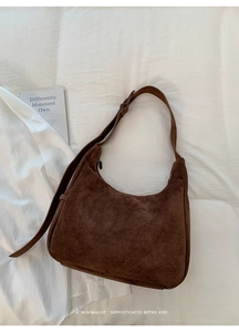 Detail of soft brown suede texture and adjustable leather strap on a large hobo bag