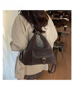 Detail of a dark brown Hobo bag with white contrast stitching and a front buckled pocket