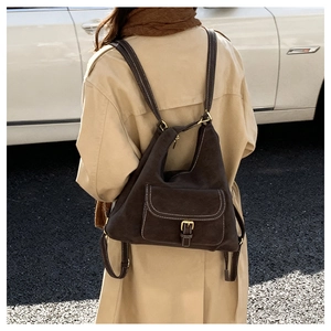 Close-up of brown suede bag with white contrast stitching and gold buckle on street