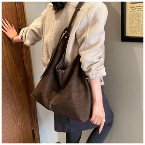 Détail du sac hobo en daim marron foncé avec coutures décoratives blanches contrastées
