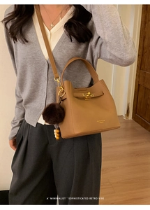 Détail d'un sac à bandoulière marron avec fermoir tournant doré et chic breloque en peluche