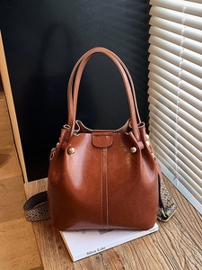 Sac seau vintage en cuir marron foncé avec large bandoulière rayée sur bois