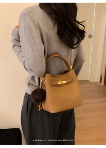 Détail du sac seau marron avec fermoir doré et décoration de pompon en peluche douce