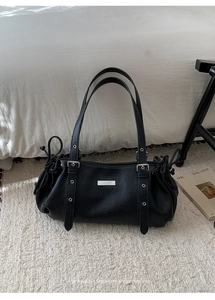 Detail of black pebbled leather shoulder bag with silver hardware and chic drawstring side