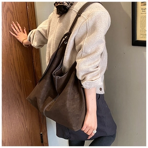Détail d'un cabas en daim marron foncé avec des surpiqûres blanches contrastées