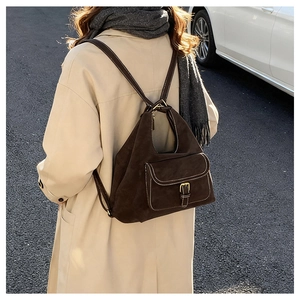 Detail of dark brown suede backpack with golden metal buckle on a beige trench coat