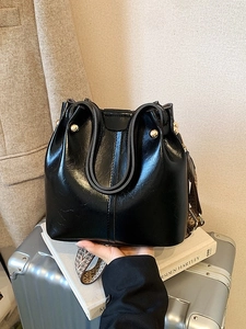 Sac seau en cuir noir minimaliste avec large bandoulière et rivets dorés en métal