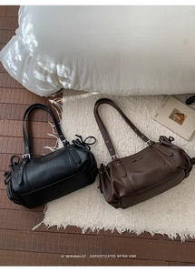 Detail of minimalist leather shoulder bags featuring silver buckles and side drawstring design