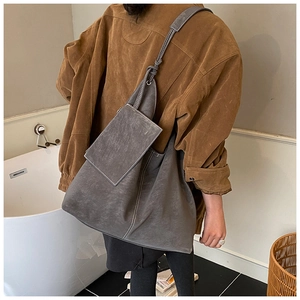 Détail du sac hobo en daim gris avec surpiqûres contrastées et petite pochette assortie