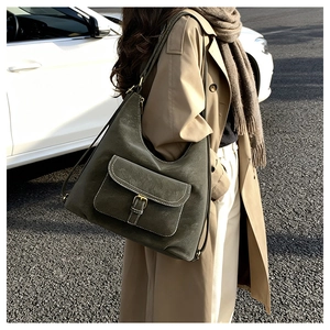 Olive green suede hobo bag with gold buckle detail worn by a model in a trench coat