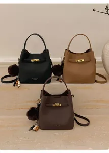Détail de sacs seaux en cuir grainé avec boucles dorées et pompons décoratifs en peluche