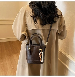 Dark brown PU leather bucket bag styled with a khaki coat and beaded charm detail