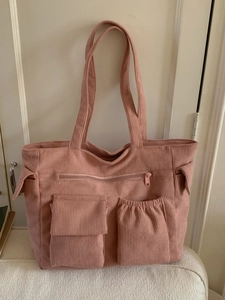 Pink corduroy tote bag with multiple front pockets and zip detail for casual use
