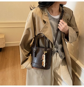 Detail of dark brown leather bucket bag with beaded charm and Fashion & YM logo print