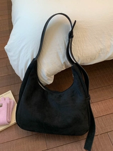 Black suede hobo shoulder bag with adjustable strap in a cozy home setting decor