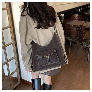 Detail of dark brown leather crescent bag with white stitching shown in a cafe setting