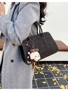 Détail du sac cabas marron mat avec breloque chiot en peluche et large bandoulière texturée