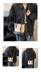 Detail view of cream and brown PU bucket bag with wooden bead tassel and gold logo
