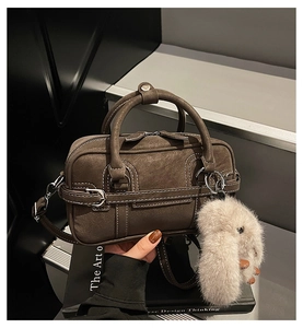 Détail du sac vintage marron avec surpiqûres contrastées et breloque lapin en peluche