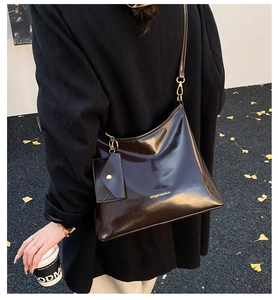 Deep brown glossy leather tote bag with small zipper charm and gold logo detail