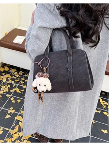 Détail d'un sac à main en simili cuir avec pendentif chien en peluche sur un manteau