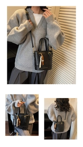 Close-up of black PU bucket bag featuring wooden bead tassel and gold hardware detail