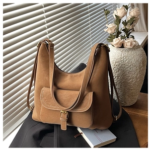 Detail of caramel hobo bag featuring white contrast stitching and gold buckle pocket
