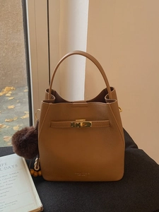 Sac seau en cuir caramel avec poignée et pompon décoratif dans un style minimaliste