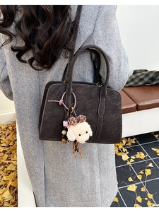Détail d'un sac à main en daim marron foncé avec un charmant pendentif chien en peluche doux