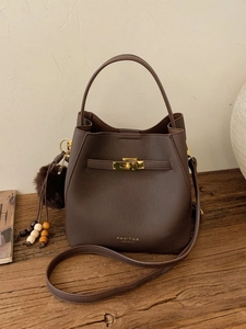 Sac seau élégant en cuir marron foncé hiver 2025 avec fermoir doré et pompon chic