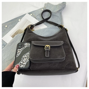 Detail of black hobo bag showing white contrast stitching and buckle pocket on leather