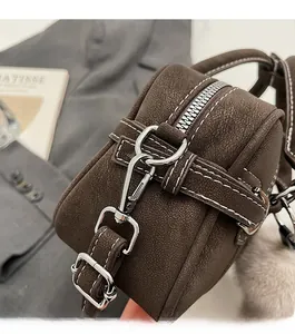 Détail du sac en cuir marron avec ferrures argentées et surpiqûres blanches contrastées