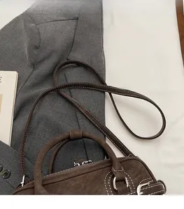 Détail du sac à main en cuir marron foncé avec surpiqûres blanches et ferrures argentées