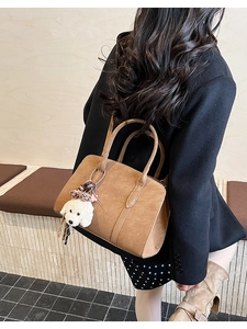 Sac fourre-tout en cuir marron avec breloque chien en peluche vu de dos par le modèle