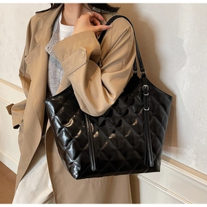 Macro detail of black quilted tote bag with glossy finish and adjustable shoulder strap