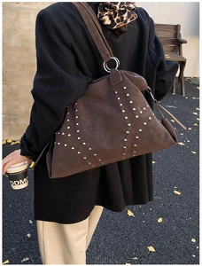 Detail of a large brown suede tote bag with silver rivets and wide shoulder strap