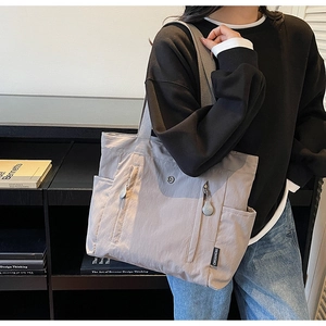 Detailed view of gray waterproof nylon tote bag with wide straps and external pockets