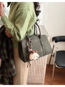 Détail du sac à main en cuir vert olive foncé avec breloque chien et couture décorative