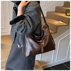Detail of dark brown tote bag with contrast stitching and decorative metal hardware
